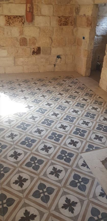 Sol en carreaux de ciment à motifs posé sous des murs en pierre apparente
