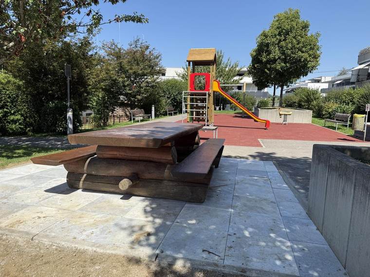 Table de pique-nique en bois massif devant la place de jeux rénovée