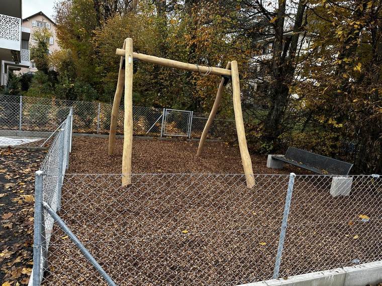 Portique de balançoire en bois rond sur sol amortissant en copeaux