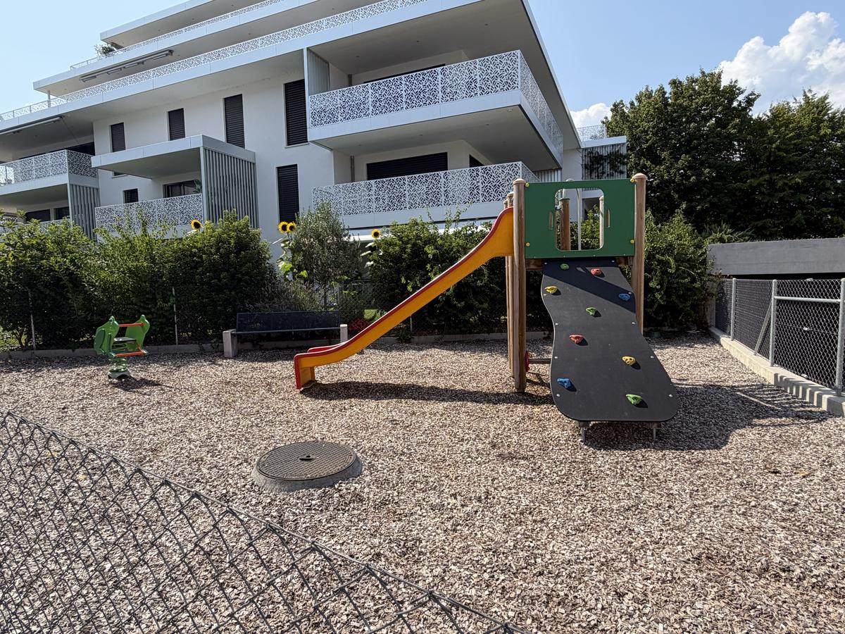Place de jeux d'une résidence à Nyon, toboggan et mur d'escalade