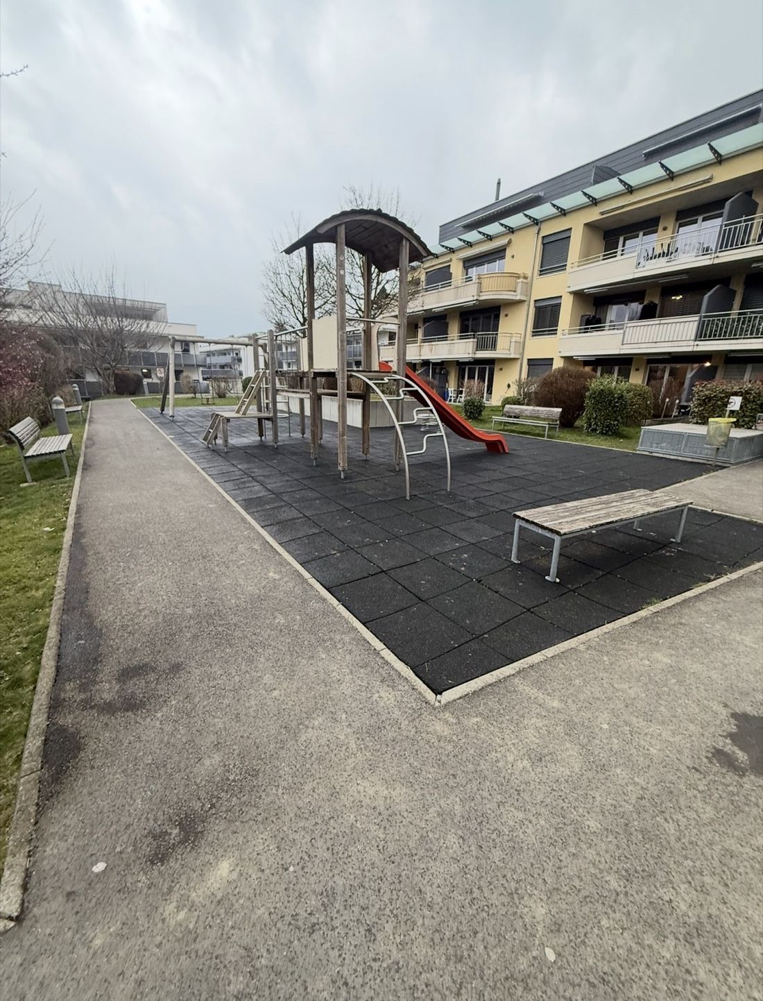 Ancienne place de jeux, structure en bois usée et sol noir