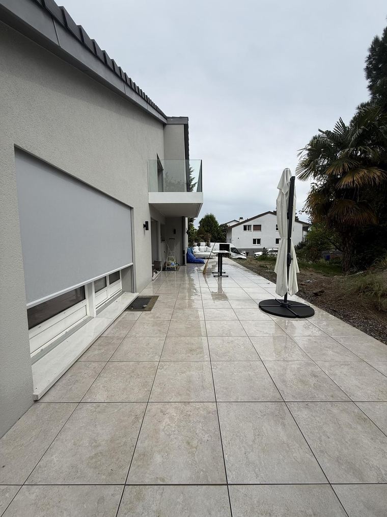 Terrasse en grès cérame crème longeant la façade de la villa